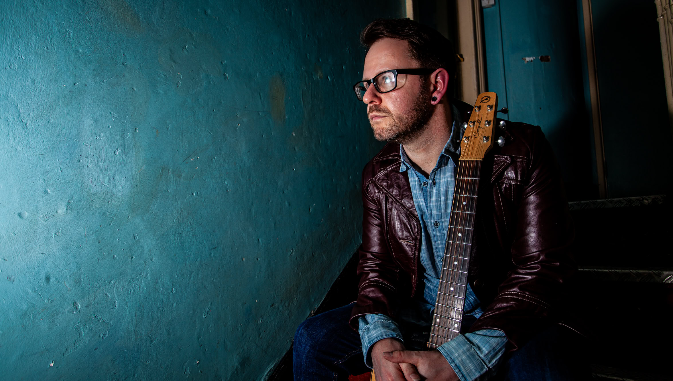 Image of singer, songwriter and composer, Del Scott Miller sat at a table by himself in a pub.